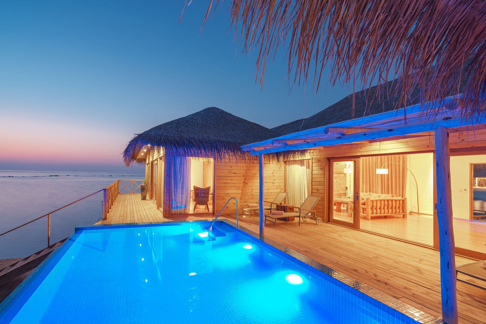 Overwater bungalow with a private infinity pool at sunset
