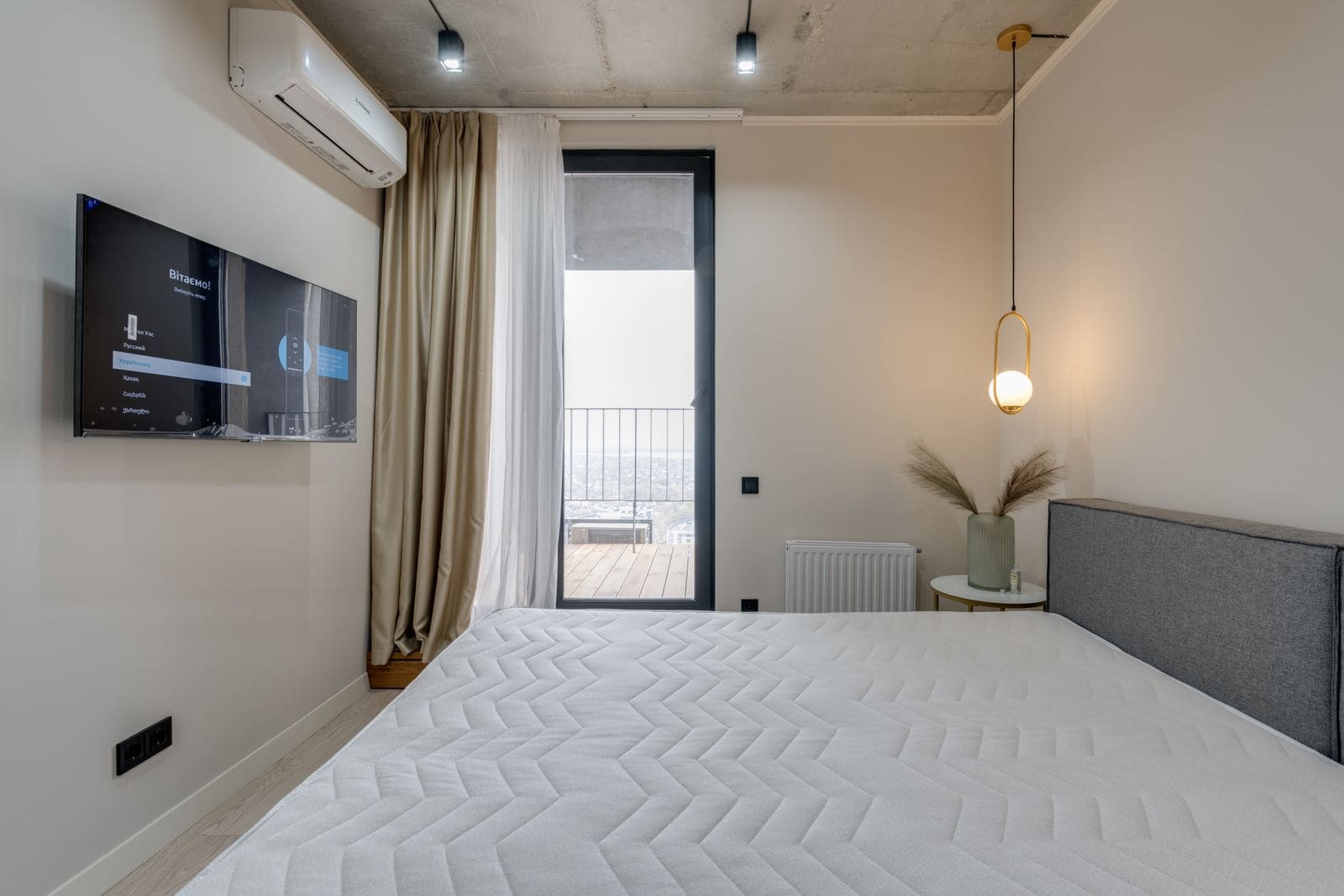 Minimalist hotel bedroom with a balcony door, wall-mounted television and soft lighting