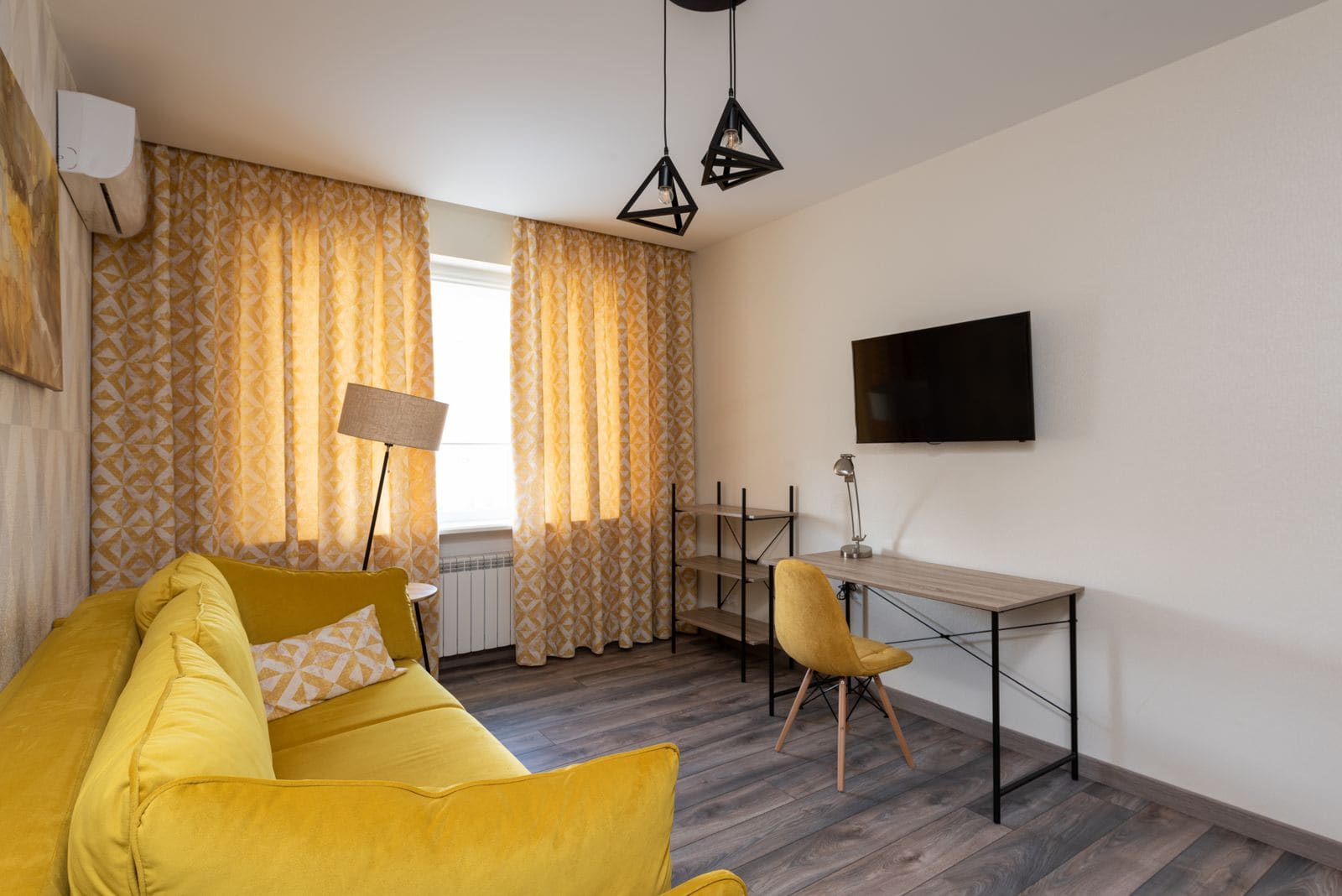 Apartment living room with a yellow sofa, geometric decor and plenty of daylight
