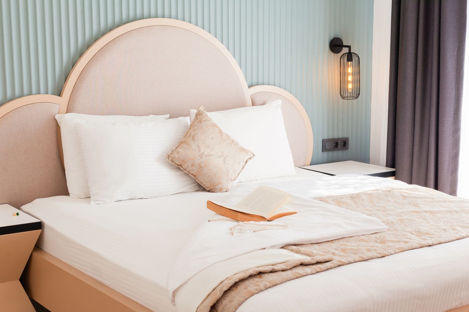 Decorative pillows and an open book arranged on a made hotel bed