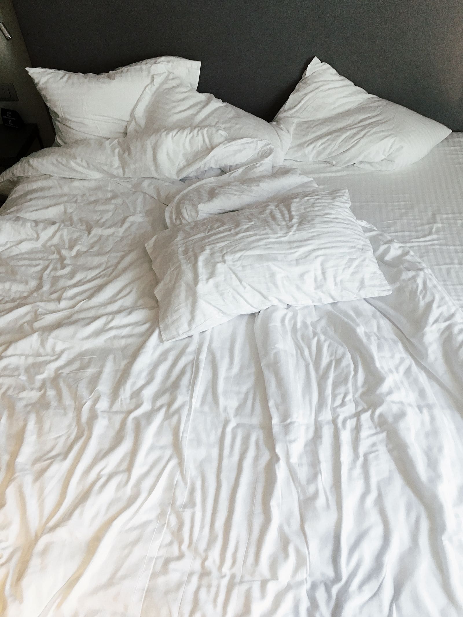Inviting unmade bed with white linens and stacked pillows in a modern bedroom