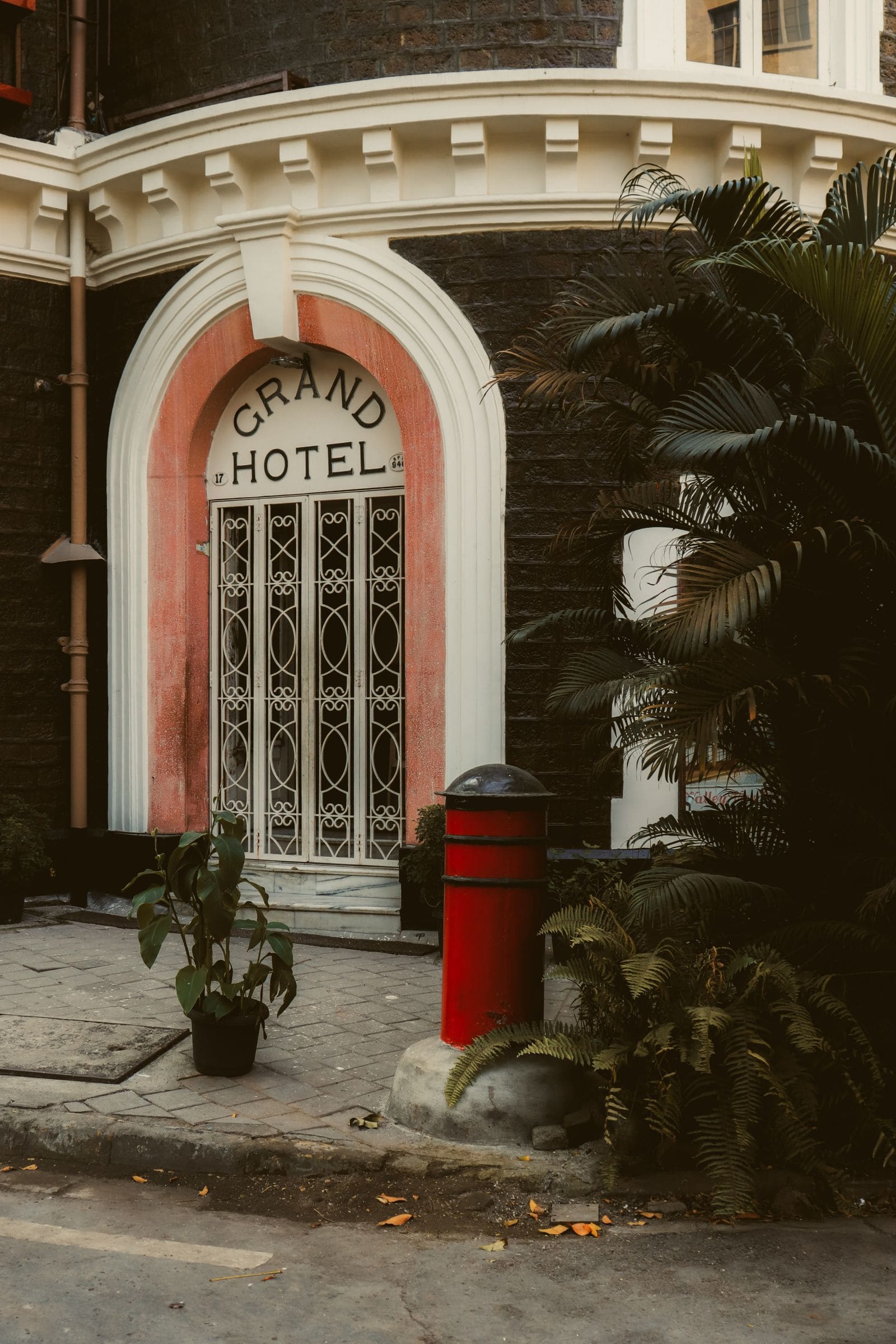Vintage entrance of a grand hotel framed by lush greenery