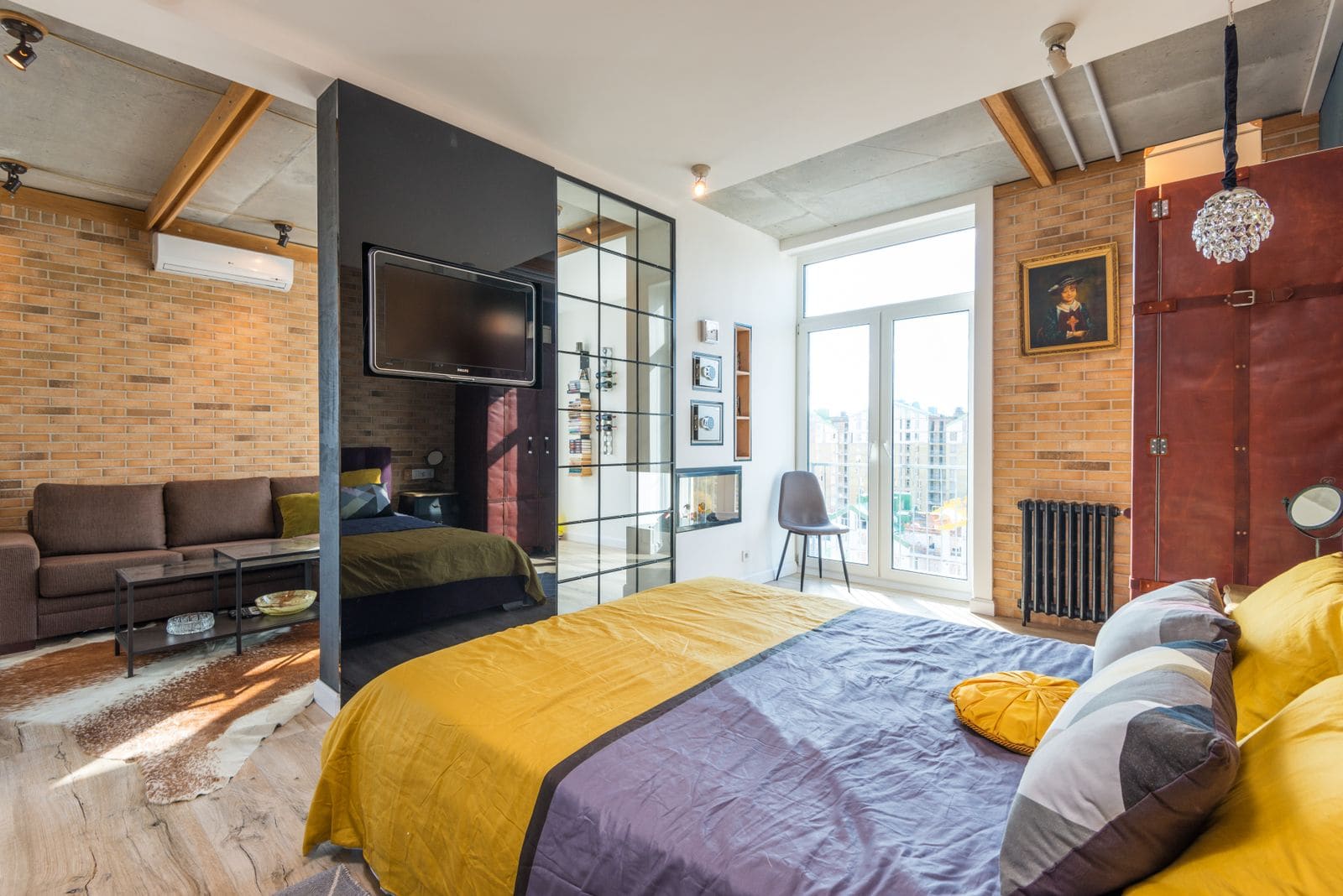 Contemporary bedroom with a yellow bedspread against an exposed brick wall