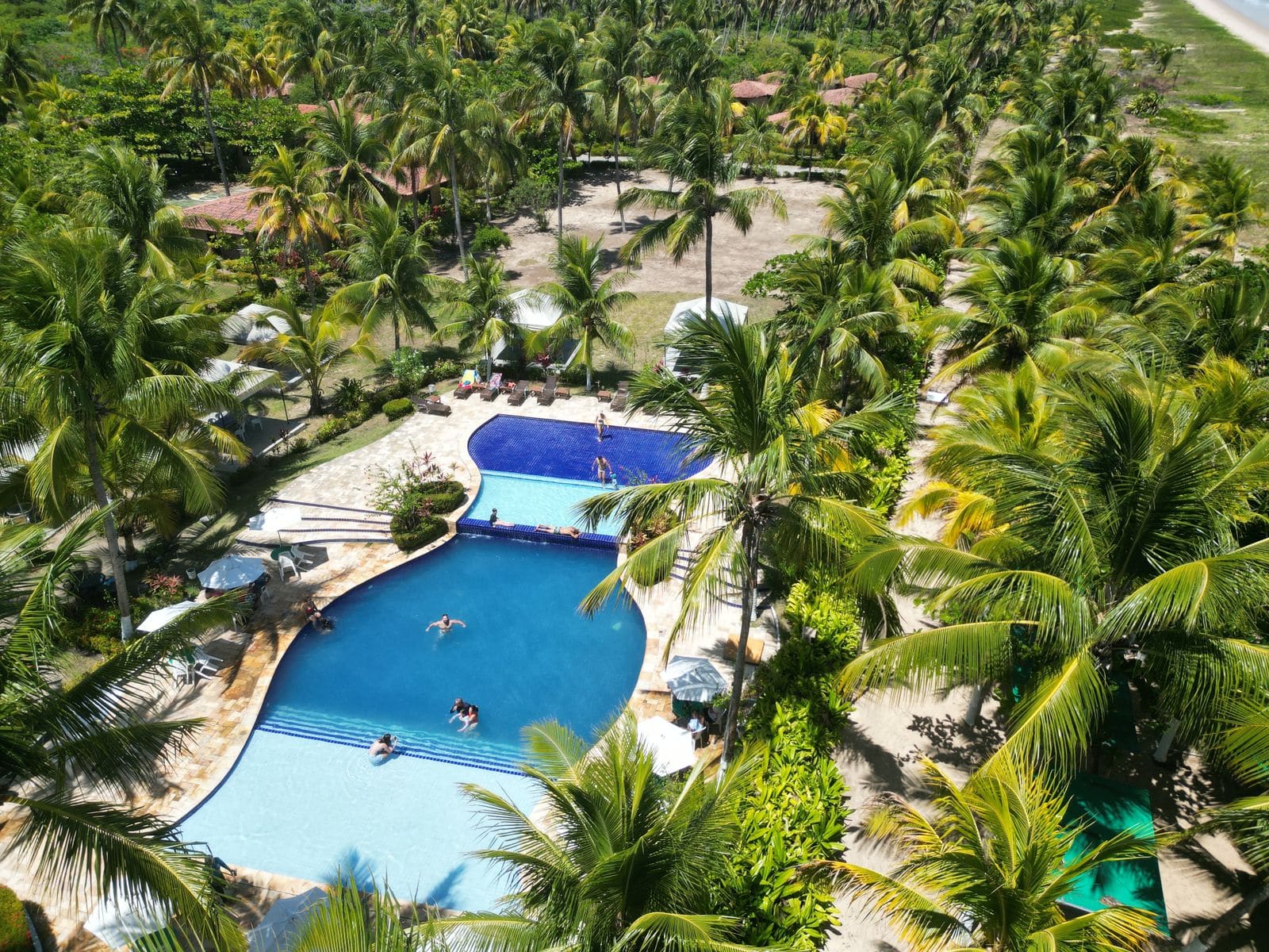 Aerial view of a tropical resort with pools and palm trees