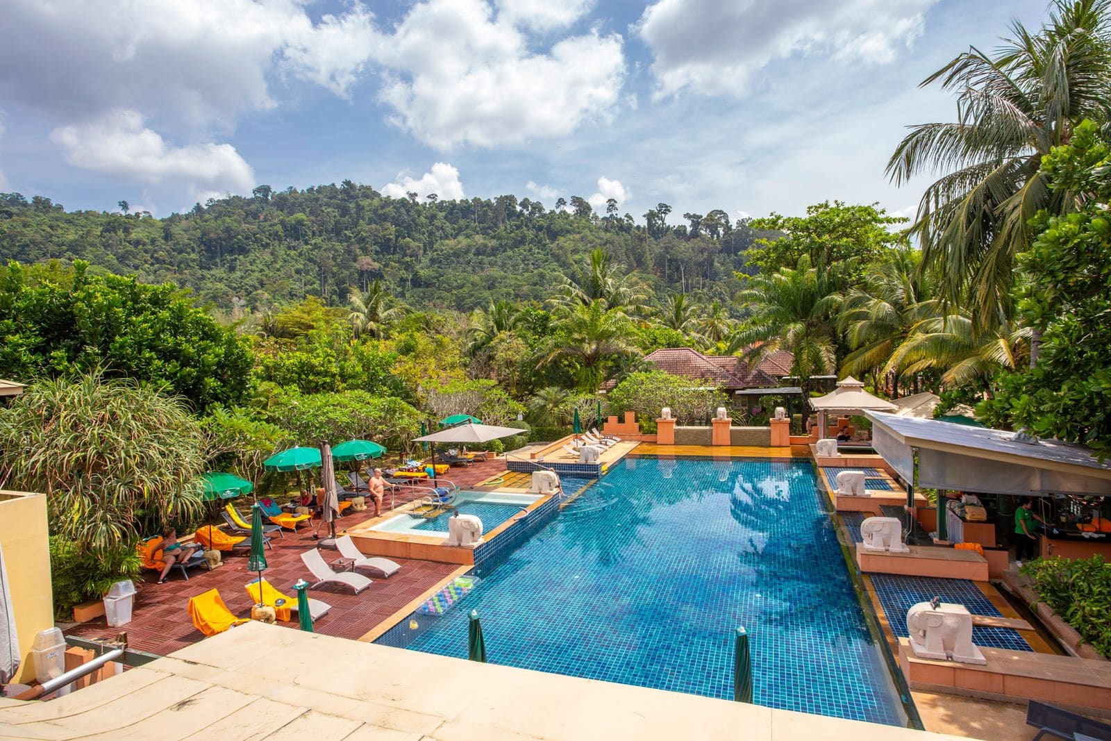 A pool surrounded by trees and lounge chairs