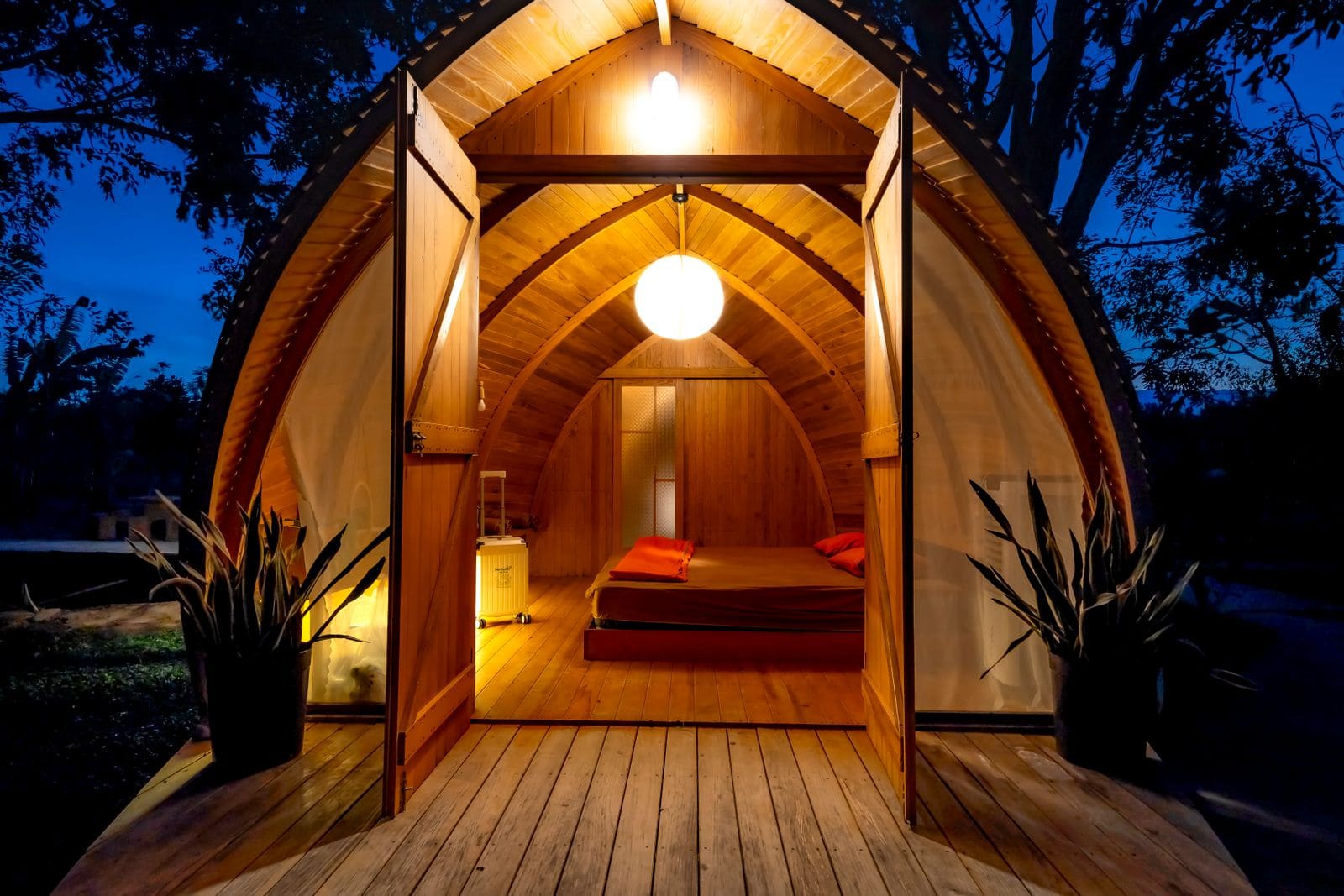 Cozy wooden cabin lit up at night with open doors
