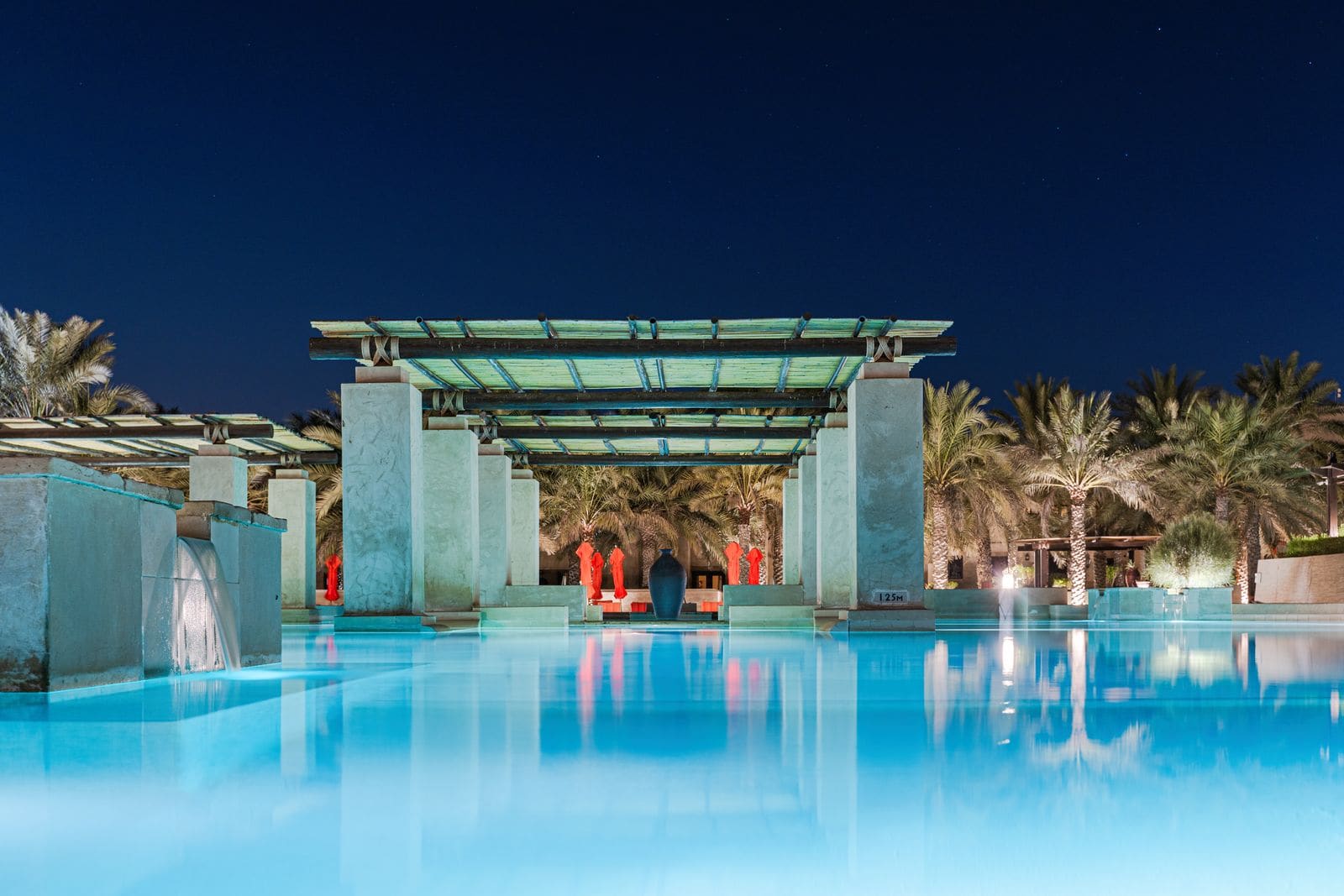 Hotel swimming pool ringed by palm trees at night