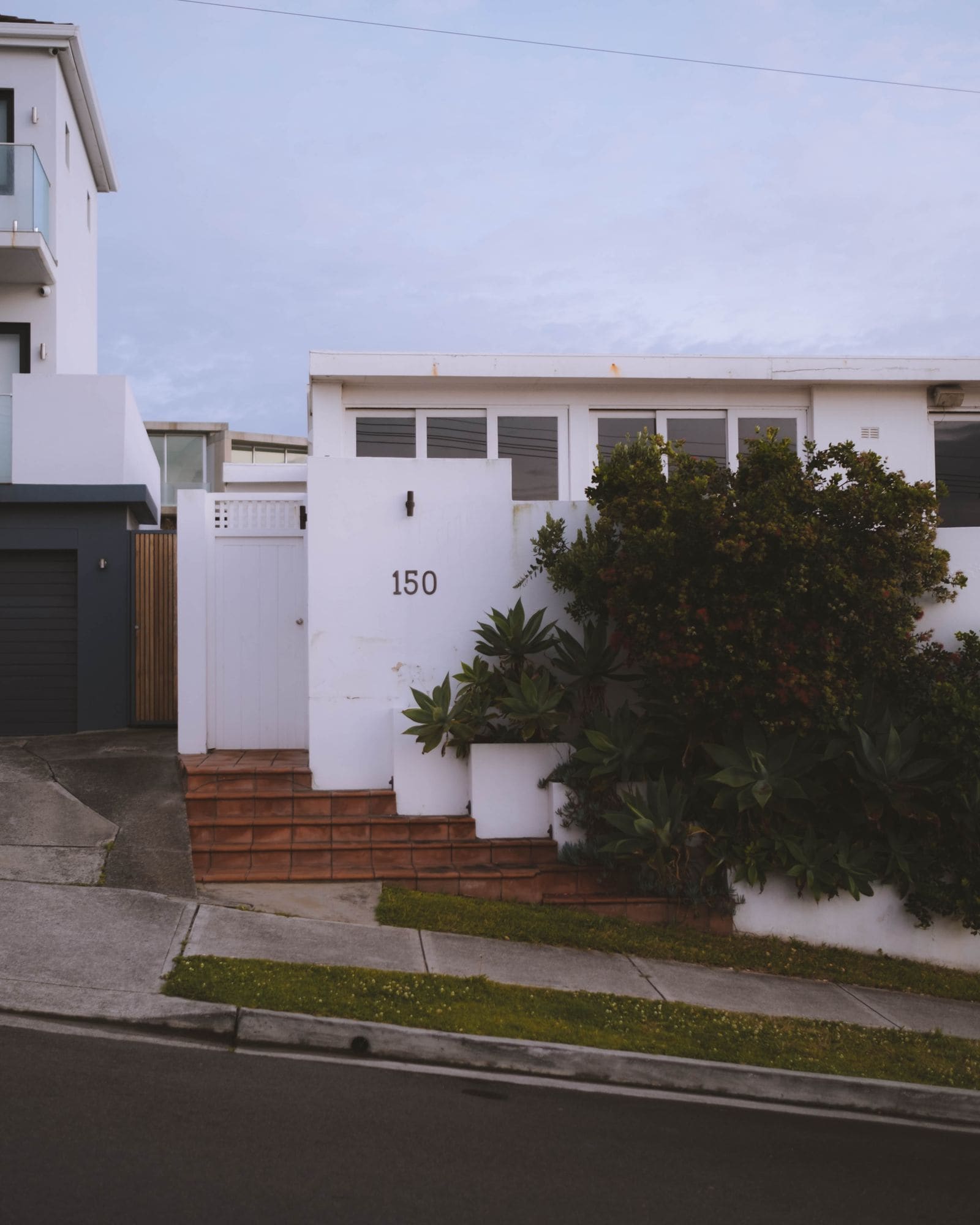 Modern villa exterior with clean lines and greenery in a quiet residential street